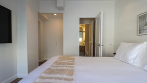 Ein Hotelzimmer mit einem großen Bett, einem an der Wand befestigten Fernseher und einer Tür zu einem Badezimmer.