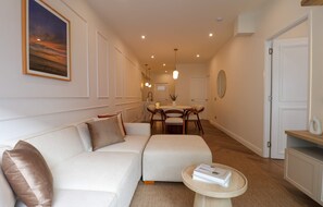 Ein modernes Wohnzimmer mit einer Couch, einem Esstisch mit Stühlen und einem kleinen runden Tisch mit einem Buch.