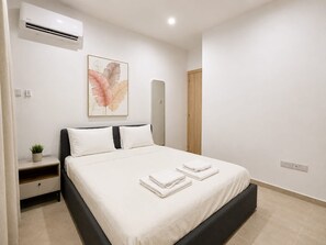 A bedroom with a bed, a nightstand with a plant, an air conditioning unit, and a framed artwork on the wall. - City Center Apartment Ermou Street (Larnaca)