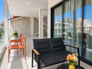 A modern balcony with a sofa, chairs, and a table with a vase of flowers. - City Center Apartment Ermou Street (Larnaca)