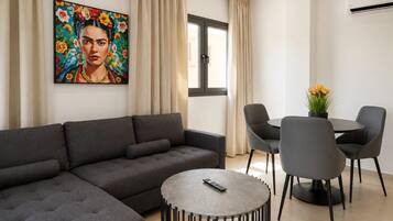 A modern living room with a grey sectional sofa, a round coffee table, and a dining area with a small table and four chairs.