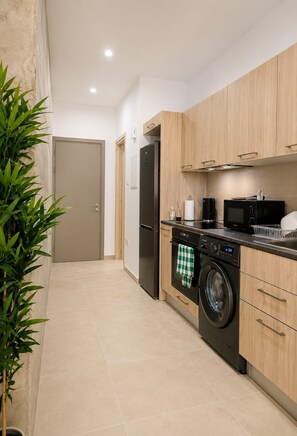 A modern kitchen with a washing machine, microwave, and a refrigerator. - City Center Apartment Ermou Street (Larnaca)