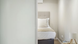 Quarto com cama, mesa de cabeceira e luminária.
