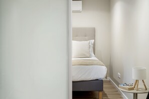 A bedroom with a bed, bedside table, and a lamp. - Oceanea Apartment by Homie (Santa Cruz)