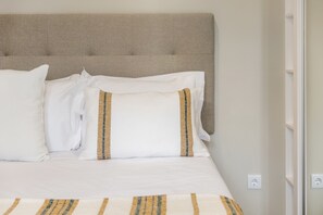 A bed with a headboard, white bedding, and a striped blanket.