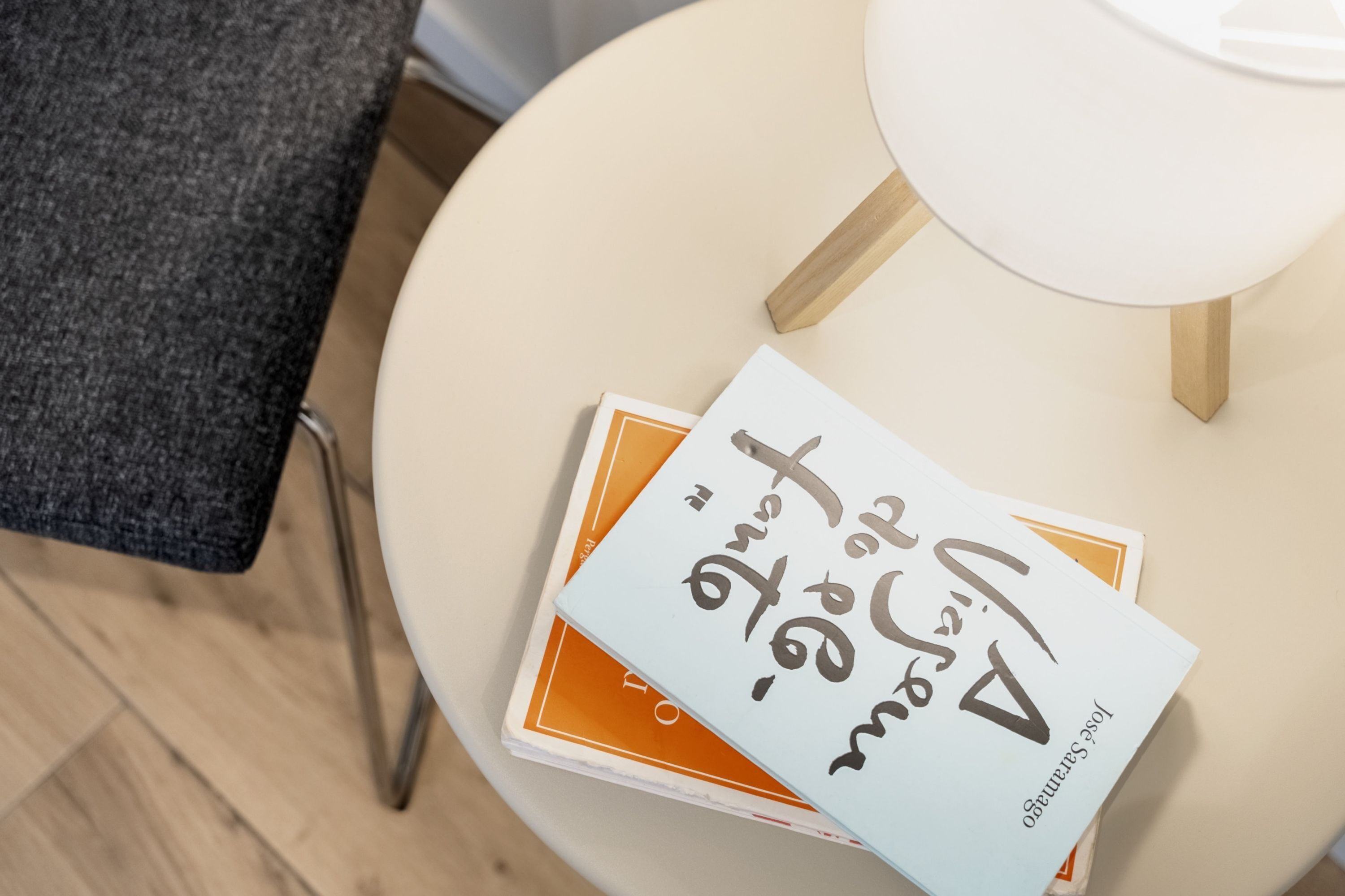 A round table with a white lamp and two books stacked on it.