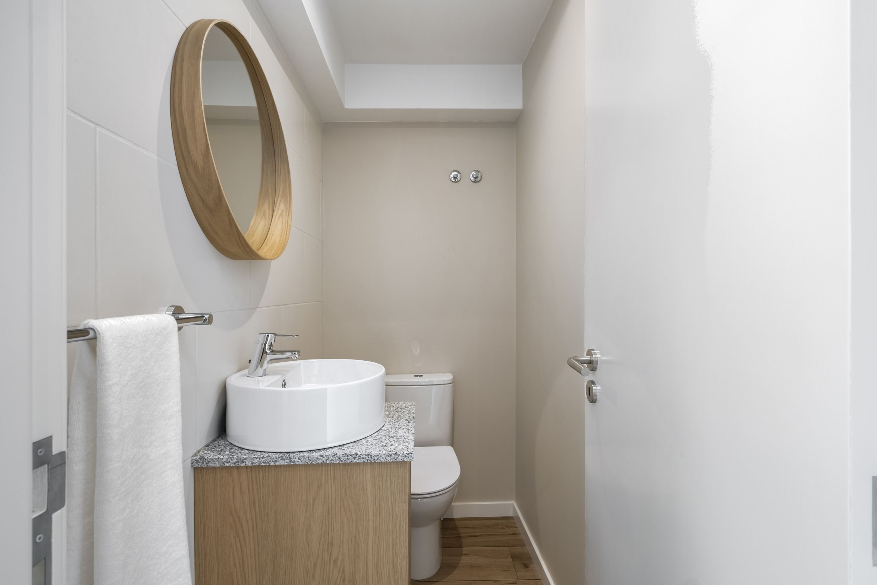 Une salle de bain avec un miroir rond, un lavabo et des toilettes.