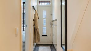 A hallway with a coat rack, a door with a window, and a mirror on the wall. - Urban Oasis With Garden in Rotterdam (Rotterdam)
