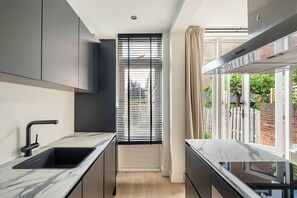 Eine moderne Küche mit schwarzem Arbeitsplatz, einer Spüle und einem Fenster mit Jalousien.