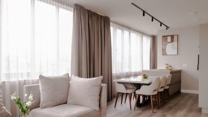 A modern living room with a sofa, a round coffee table, and a dining area with chairs and a table. - 2BR Rooftop Terrace in Rotterdam City Centre (Rotterdam)