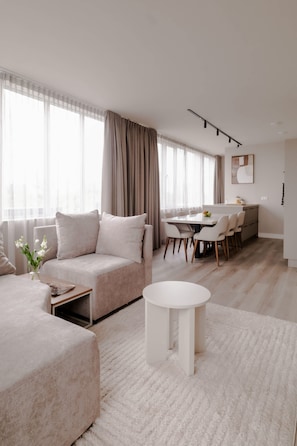 A modern living room with a sofa, a round coffee table, and a dining area with chairs and a table. - 2BR Rooftop Terrace in Rotterdam City Centre (Rotterdam)