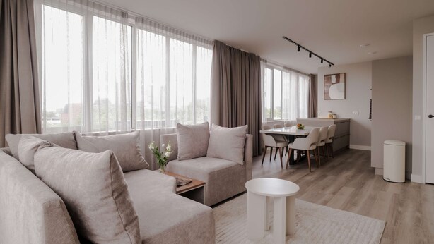 A modern living room with a sofa set, a dining area, and a kitchen in the background. - 2BR Rooftop Terrace in Rotterdam City Centre (Rotterdam)