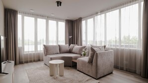 A modern living room with a sectional sofa, a small round table, and a flat-screen TV. - 2BR Rooftop Terrace in Rotterdam City Centre (Rotterdam)