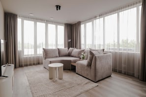 A modern living room with a sectional sofa, a small round table, and a flat-screen TV. - 2BR Rooftop Terrace in Rotterdam City Centre (Rotterdam)