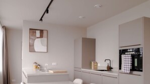 A modern kitchen with a central island, white cabinetry, and a dining area with a white table and chairs. - 2BR Rooftop Terrace in Rotterdam City Centre (Rotterdam)
