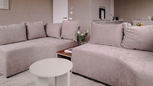 A modern living room with a sectional sofa, a round coffee table, and a white rug. - City Center Penthouse w Free Parking City Views (Rotterdam)
