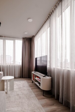 Uma sala de estar moderna com uma televisão de tela plana, um sofá branco e uma mesa de centro branca.