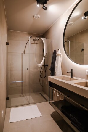 Uma casa de banho moderna com chuveiro em cabine de vidro, um espelho grande e um lavatório com pia.