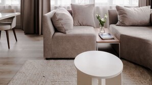 A modern living room with a sectional sofa, a round coffee table, and a dining area with a table and chairs. - 2BR Penthouse Rotterdam City Centre (Rotterdam)