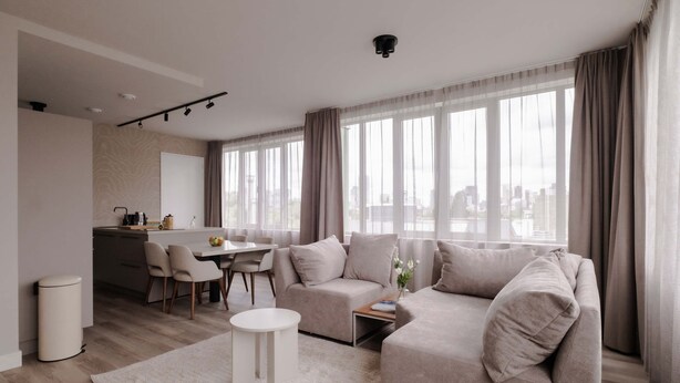 A modern living room with a sofa, a dining table, and a kitchen area. - 2BR Penthouse Rotterdam City Centre (Rotterdam)