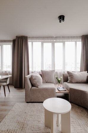 Ein modernes Wohnzimmer mit einer Eckcouch, einem runden Couchtisch und einem Essbereich mit Tisch und Stühlen.