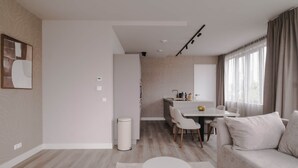 A modern living room with a sofa, a round coffee table, and a dining area with a table and chairs. - 2BR Penthouse Rotterdam City Centre (Rotterdam)