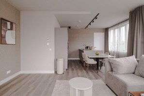 A modern living room with a sofa, a round coffee table, and a dining area with a table and chairs. - 2BR Penthouse Rotterdam City Centre (Rotterdam)