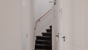 Um corredor com piso de madeira que leva a uma escada com corrimão.