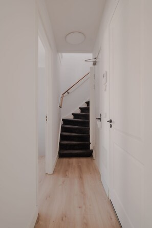 Ein Korridor mit Holzboden, der zu einer Treppe mit Handlauf führt.