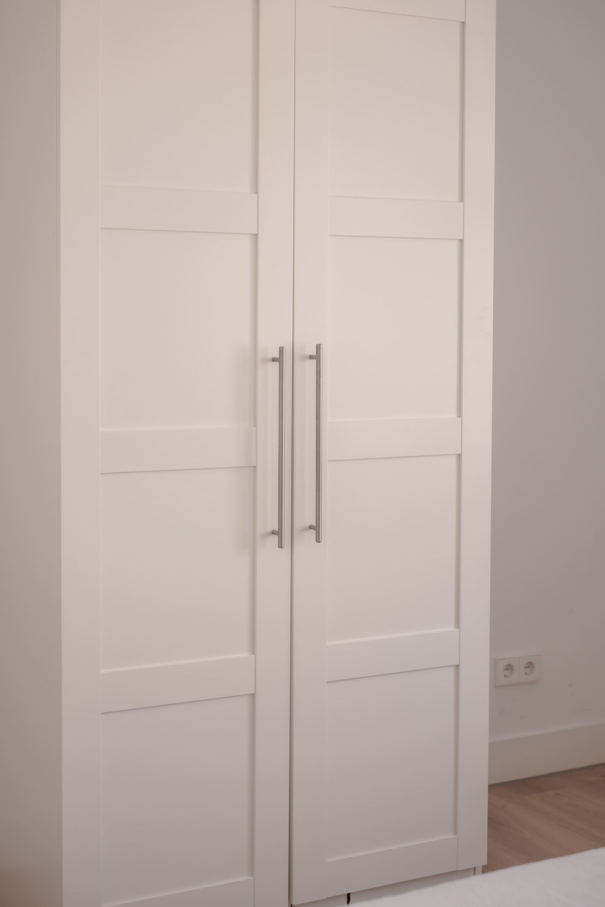 A white wardrobe with two doors and a handle.