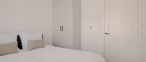 A bedroom with a bed, pillows, a wardrobe, and a door.