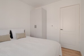Quarto com cama, almofadas, guarda-roupa e porta.