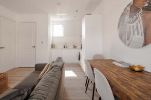 A modern interior with a sofa, dining table, and kitchen area. - In het Hart van Schiedam Rotterdam om de Hoek (Schiedam)