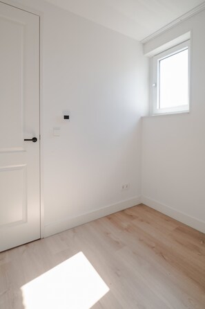 A room with a white door, a small window, and a light switch on the wall. - In het Hart van Schiedam Rotterdam om de Hoek (Schiedam)