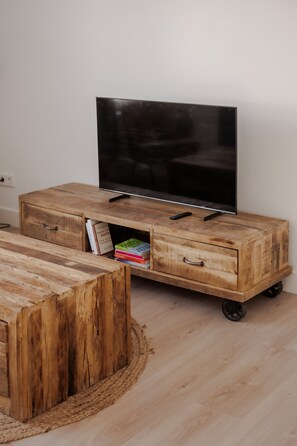 A wooden entertainment unit with a flat-screen TV, drawers, and a small coffee table. - In het Hart van Schiedam Rotterdam om de Hoek (Schiedam)