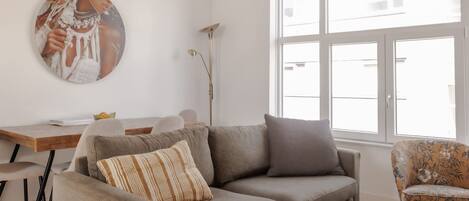 A modern living room with a sofa, coffee table, and a painting on the wall.