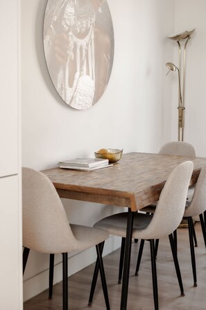 A dining area with a wooden table, four chairs, a round mirror on the wall, and a floor lamp. - In het Hart van Schiedam Rotterdam om de Hoek (Schiedam)