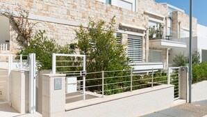 A modern building with a stone facade, a gated entrance, and a balcony. - Cala Bianca Hideaway by Wonderful Italy (Polignano a Mare)