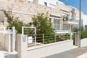 A modern building with a stone facade, a gated entrance, and a balcony. - Cala Bianca Hideaway by Wonderful Italy (Polignano a Mare)