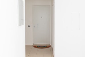 A white door with a handle, a small window, and a colorful rug on the floor. - Cala Bianca Hideaway by Wonderful Italy (Polignano a Mare)