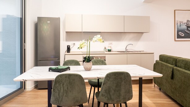 A modern kitchen with a dining area, a sofa, and a view of the city. - Cala Bianca Hideaway by Wonderful Italy (Polignano a Mare)