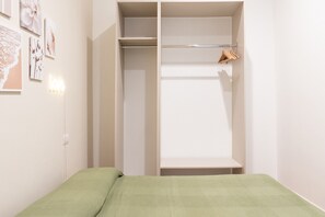 A bedroom with a bed, a wardrobe, and a shelf with clothes. - Cala Bianca Hideaway by Wonderful Italy (Polignano a Mare)