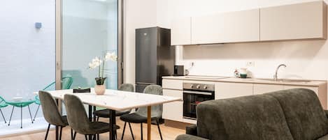 Una cocina compacta con comedor, sofá y vistas a través de un ventanal.