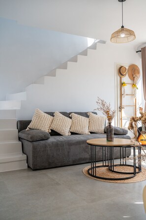 Ein modernes Wohnzimmer mit grauem Sofa, einem runden Couchtisch und einer Treppe.