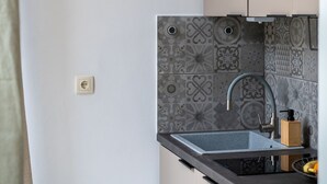 Uma cozinha com design moderno, destacando um painel de backsplash estampado, uma pia de aço inoxidável e um pendente.