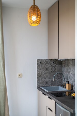 Eine Küche mit modernem Design, inklusive einer Wandfliesenverkleidung mit Muster, einer Edelstahl-Spüle und einer hängenden Leuchte.