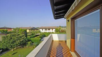 Varanda residencial com chão de azulejos, vista para casas vizinhas e céu claro.