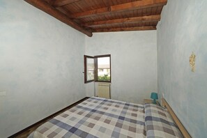 A bedroom with a checkered bedspread, a window with a view, and a radiator. - Raffa Holiday in Raffa (Puegnago del Garda)