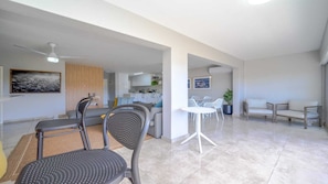 A modern living room with a dining area, a kitchen in the background, and a ceiling fan. - Durban Holiday Breeze (Durban North)