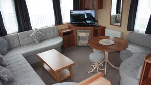 Un espacio habitable compacto con un sofá, una mesita, un televisor y un armario.